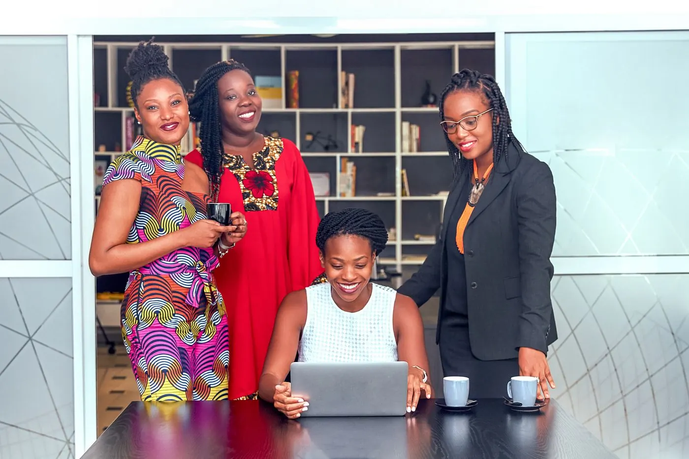 A team of women professionals working together around a laptop