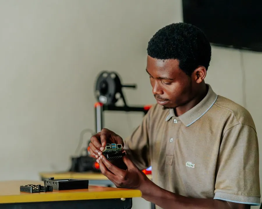 A young man assembling an electronic circuit board at a workbench