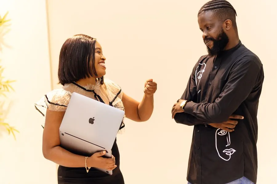 Two colleagues laughing during a discussion over a laptop
